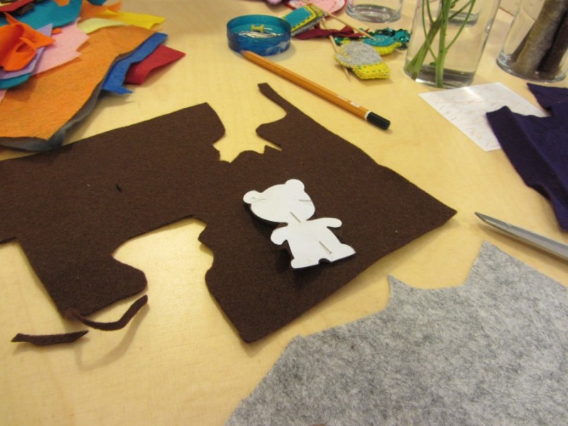 Тоді накладаю паперового ведмедика на тканину і прикріпляю до неї булавками. І знову ж таки вирізаю вже тканинного ведмедика.